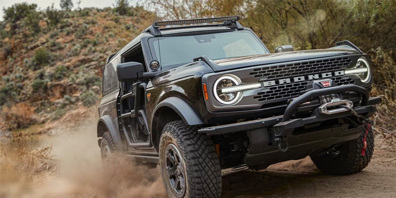 A black 2024 Ford Bronco powering uphill on a dirt road